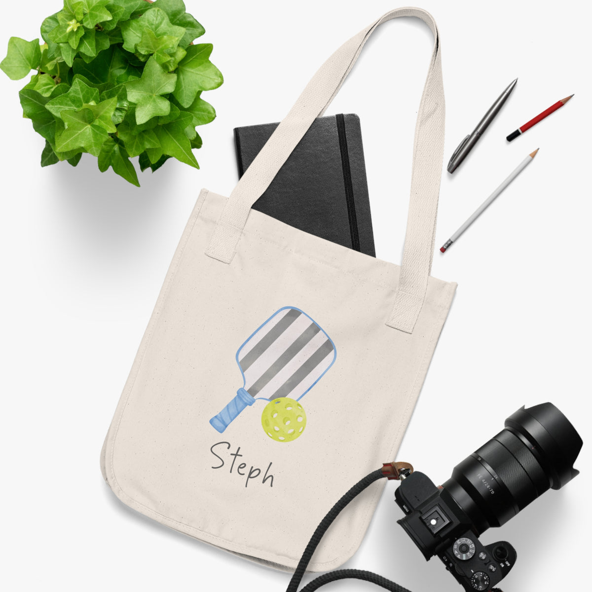 Pickleball player's personalized tote bag. An organic cotton canvas tote bag with a printed illustration of a striped pickleball paddle and a yellow pickleball, with customizable text written below, such as "Smash it!". Custom and personalized tote.